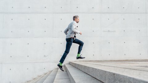 elegant bearded businessman running up stairs outdoors